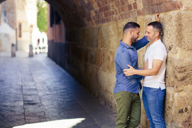 Two men facing each other and embracing under a city bridge