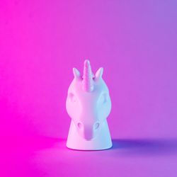 Painted unicorn head in bold pink and blue neon colors on gradient background
