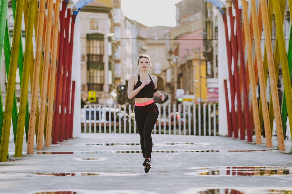 Woman with earphones running on street