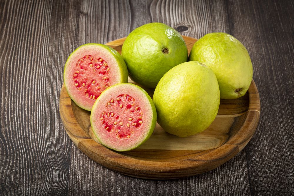 Fresh sliced guavas on wooden table.