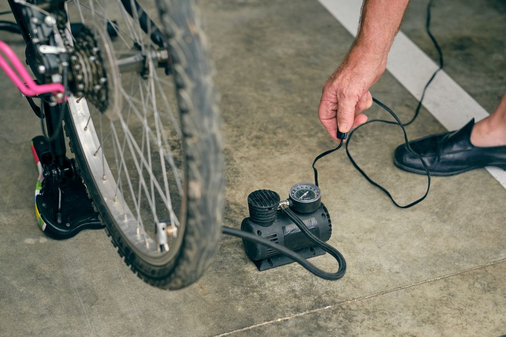 Older man inflating bicycle with compressor in garage