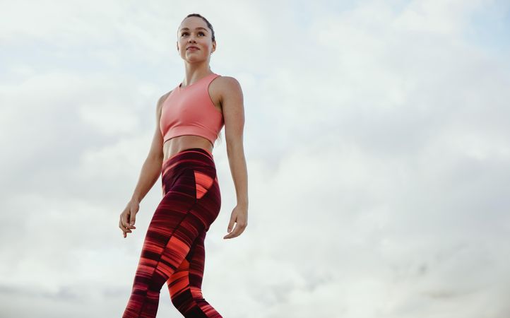 Fitness woman looking away while exercising against sky