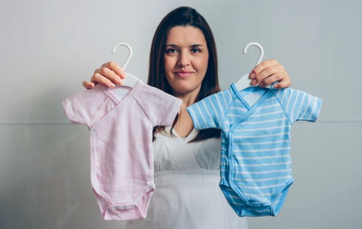 Pregnant woman showing baby bodysuits
