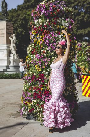 Modern woman in flamenco dress near flower wall