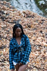 Young woman standing in front of fall leaves in fashionable outfit looking down
