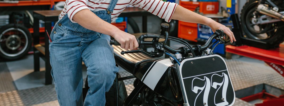 Mechanic woman starting custom motorcycle on factory