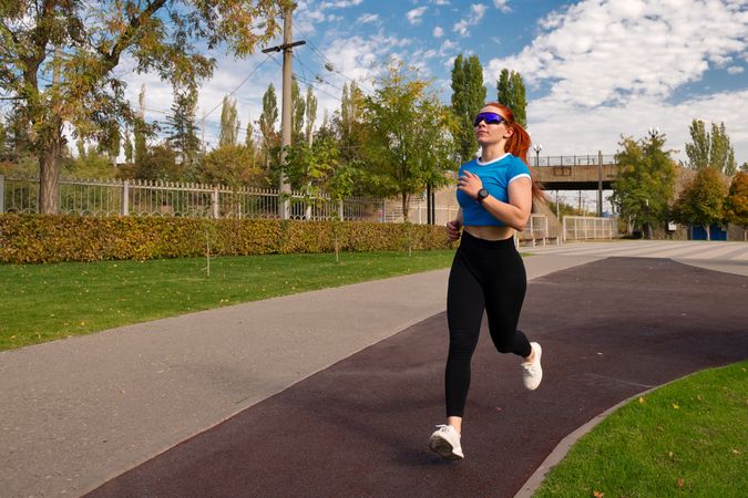 Woman running outdoors in park on sunny day.