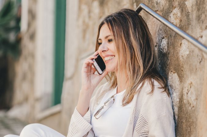 Woman with smartphone sitting on stone steps of stairs