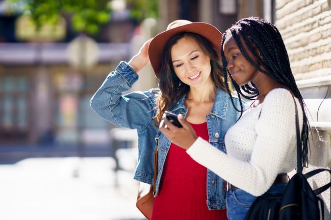 Two women checking their selfies on smartphone outdoor