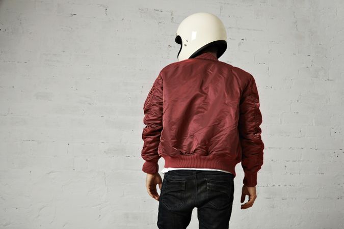 Rearshot of man in dark red leather jacket wearing helmet in studio shoot