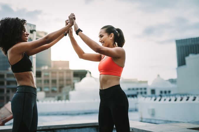 Happy fitness women giving high five after their workout on rooftop