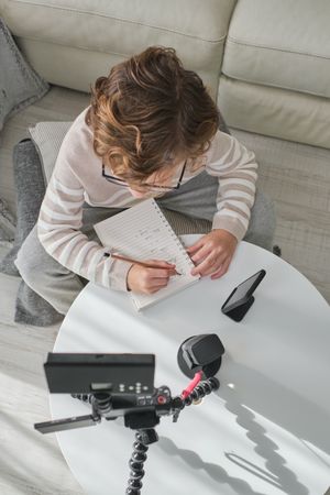 Boy writing and looking at camera
