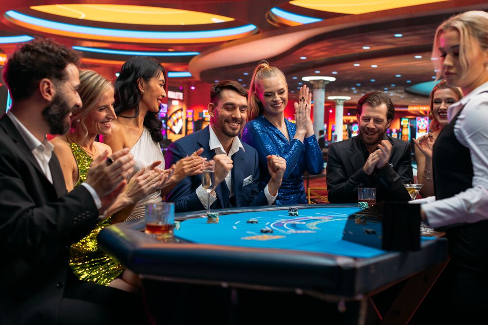 Group of Glamorous People Playing Card at Blackjack Table on a Casino Floor.