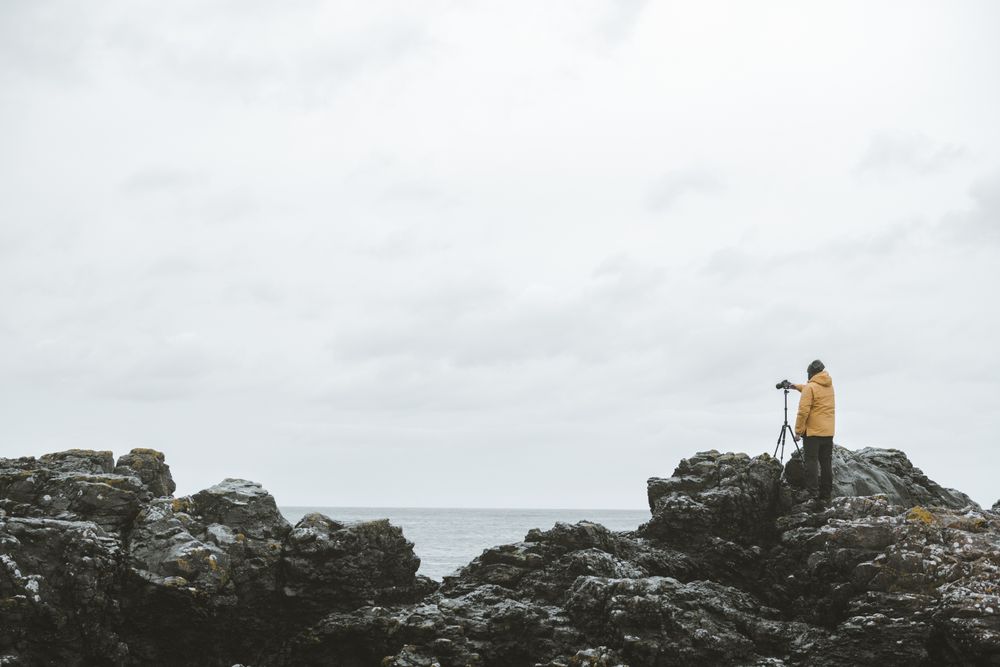 Man standing on rock and taking picture of sea