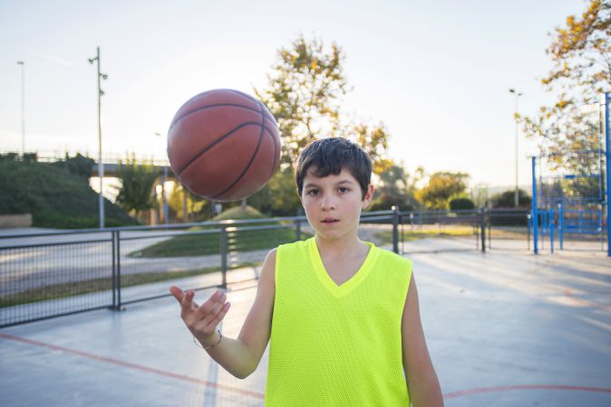 Teenage boy tossing a basketball from one hand to another on a court