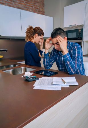 Couple arguing as they go through their bills together in the kitchen, vertical