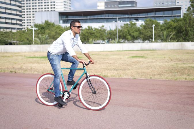 Male riding red and green bike outside