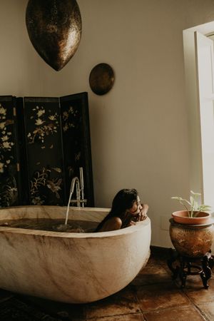Melancholic Woman sitting and washing in bath