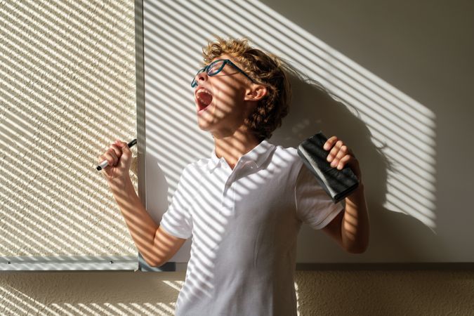 Excited schoolboy standing near whiteboard in classroom and scre