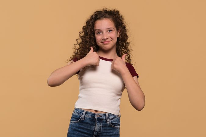 Young girl giving double thumbs-up, smiling confidently