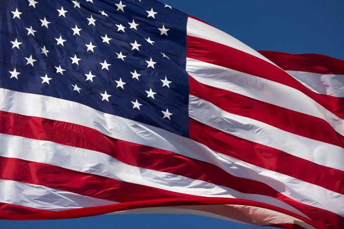 American Flag Waving In Wind Against a Deep Blue Sky.