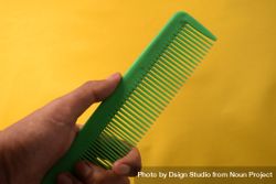 Hand with green hair comb in yellow studio 5aXonv