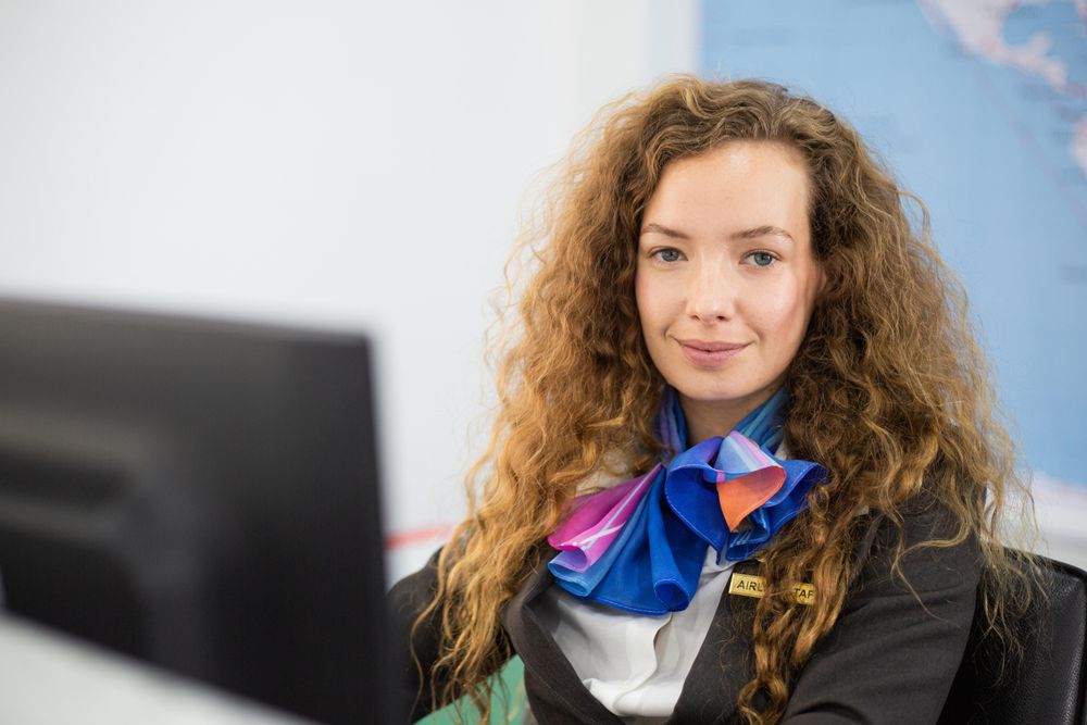 White female in flight attendant uniform working at counter