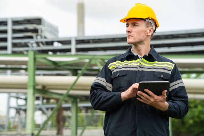 Refinery oil engineer worker in protection hardhat with digital tablet inspecting at petrochemical factory.