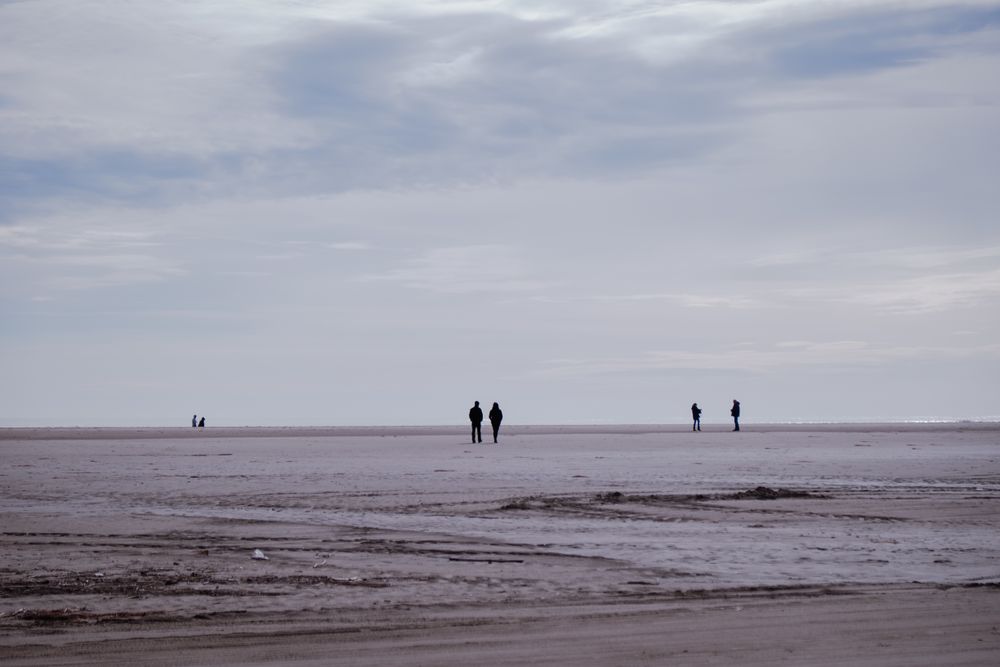 Wide sandy beach with silhouettes of people
