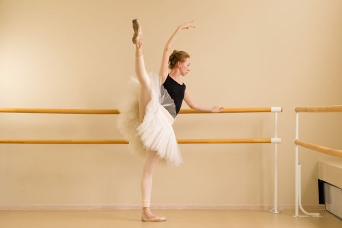 Ballet dancer performing high leg extension at barre