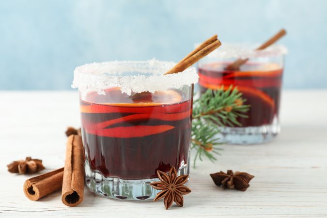 Glasses of tasty mulled wine on blue wooden background, space for text