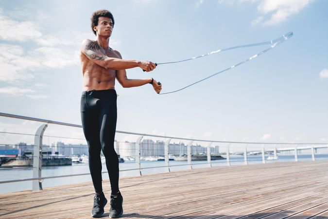 Athletic Black male working out on the water front with a jumprope