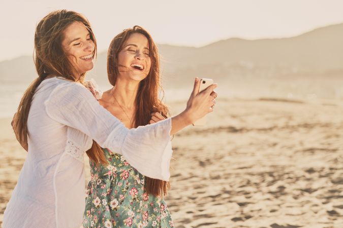 Smiling women making selfie on beach