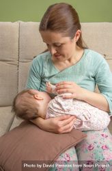 Baby breastfeeding with mother on couch, vertical 5n8G8b