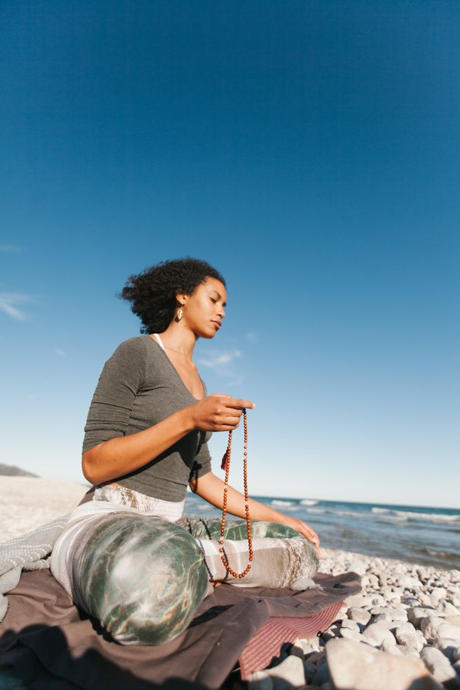 Sportive woman sitting on sandy beach in asana