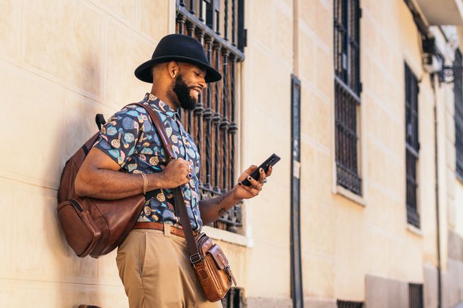 Stylish Black man in the city street using smartphone