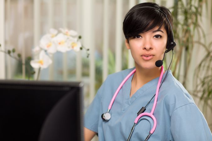 Woman Wearing Headset, Scrubs and Stethoscope