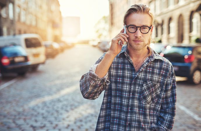 Man in glasses on his cellphone on a European cobble street