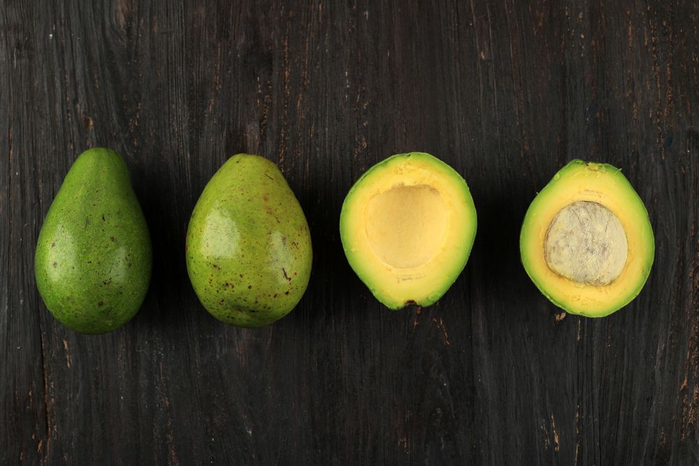 Whole avocado & avocado halves lined up on table