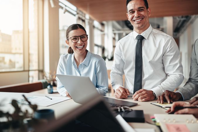 Two people smiling at work around a laptop and desk
