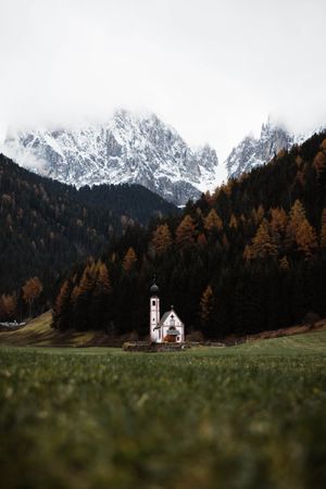 Small church on cliff near forest and mountains
