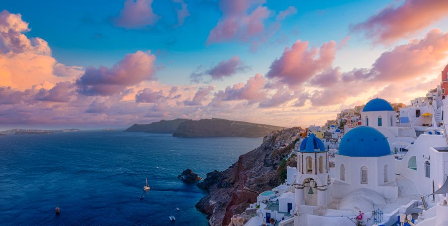 Colorful clouds over Santorini at dusk with blue domes