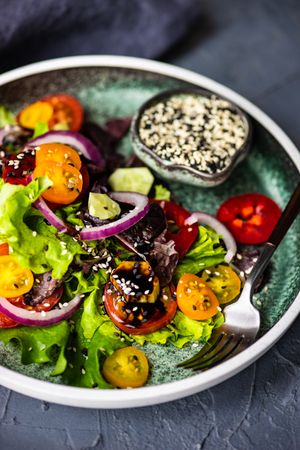 Close up of organic vegetable salad with side of sesame seeds with space for text