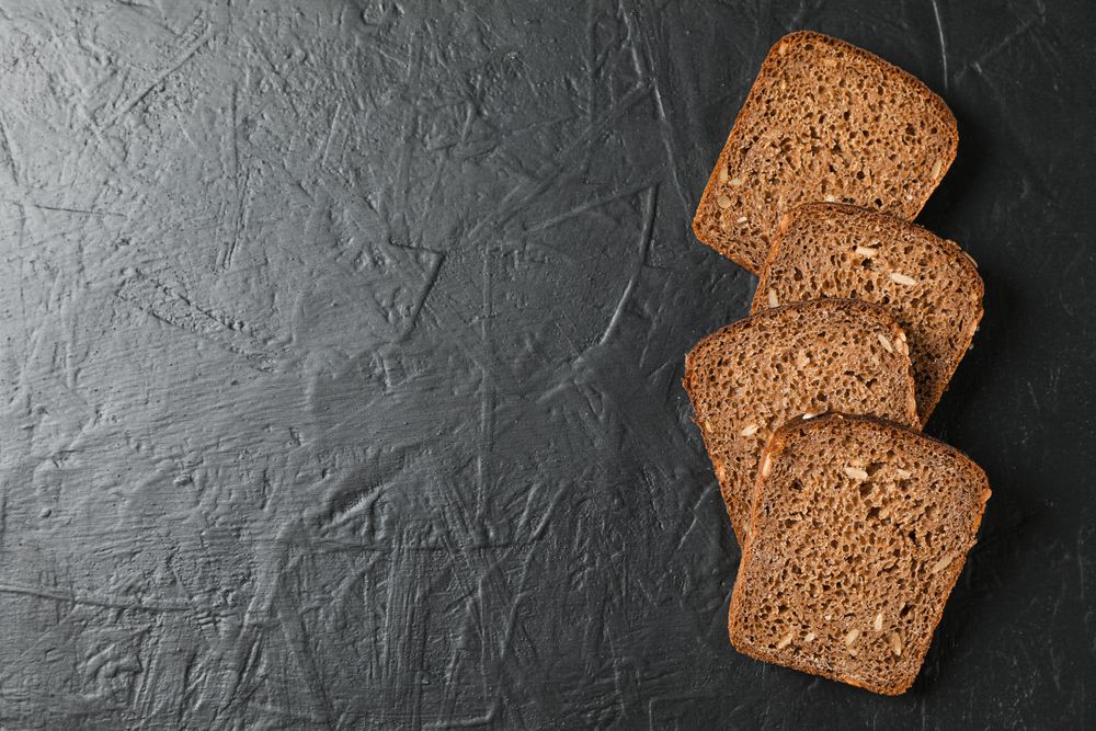Rye bread pieces on dark background, top view and space for text