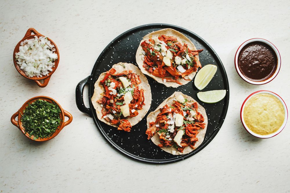 Pepper and lime near tacos al pastor and sauces