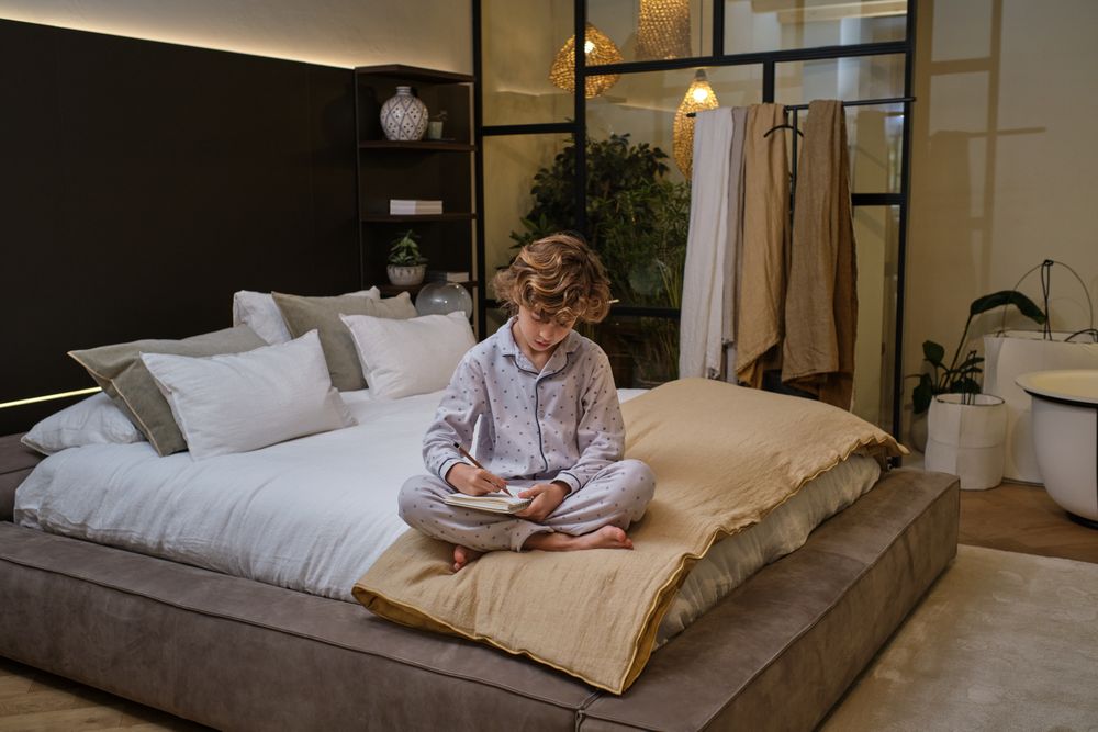 Boy writing in notebook on bed