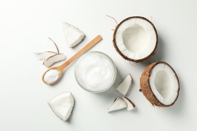Coconut and cosmetics plain background, top view