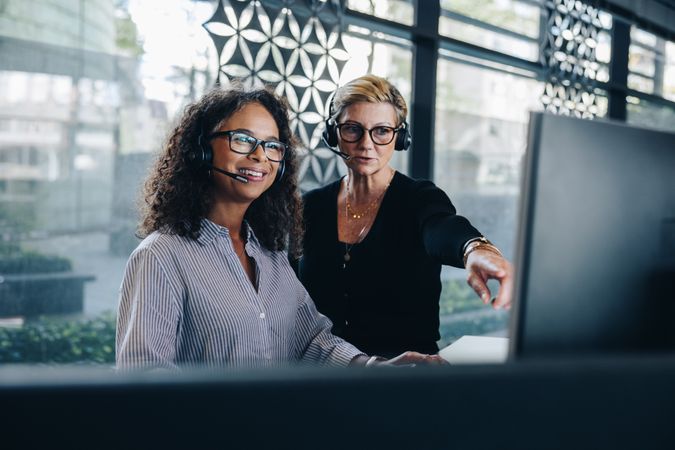 Manager helping female colleague working on computer