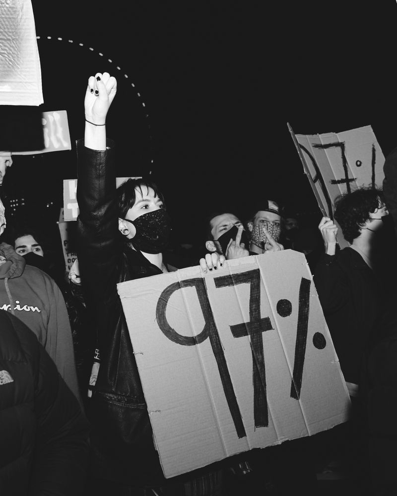 London, England, United Kingdom - March 16, 2021: Woman in crowd with raised fist and 95% sign
