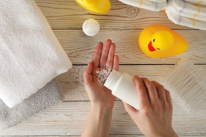 Mom applying talc powder from plastic tube. Baby hygiene